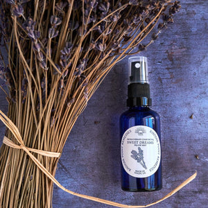 Blue spray bottle labeled 'Sweet Dreams' with lavender on a textured surface