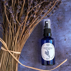 Blue spray bottle labeled 'Sweet Dreams' with lavender on a textured surface