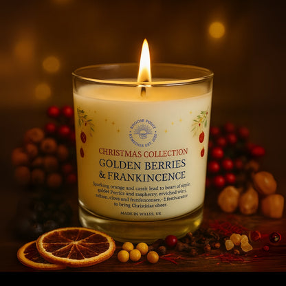 Candle labeled 'Golden Berries & Frankincense' from the Christmas Collection on a wooden surface with decorative elements.